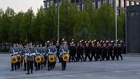 Fackelträger und Musikkorps der Bundeswehr marschieren in Formation auf dem Paradeplatz