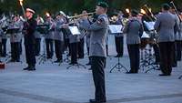 Ein Trompeter der Bundeswehr spielt Musik. Im Hintergrund weitere Soldaten beim Musizieren.