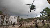 Soldiers kneeling on the ground under the helicopter at the training area