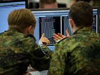 Zwei Soldaten sitzen vor einem Monitor.