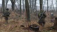 Zwei Soldaten gehen in einem Waldstück vor