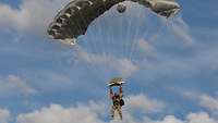 Ein Soldat schwebt an seinem Fallschirm in der Luft.