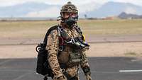 Ein Soldat mit Sauerstoffmaske, Helm, Handschuhen und Gleitfallschirm auf dem Rücken.
