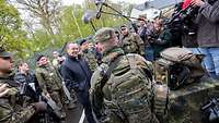 Minister Pistorius spricht im Beisein von vielen Pressevertretern mit einem Soldaten.