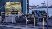 Mehrere Militärfahrzeuge werden in einem Hafen auf eine Fähre gefahren