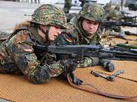 Mehrere Soldaten liegen nebeneinander auf Matten und halten Maschinengewehre in der Hand.