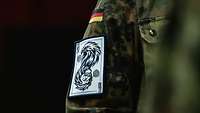 Ein blau-weißes Patch mit den Abbildungen eines Adlers und eines Löwen auf dem Arm eines Soldaten.
