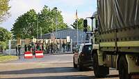 Vor einem Kasernentor findet eine Demonstration statt, die die Einfahrt komplett blockiert.