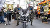 Zwei Soldaten stehen neben einem Motorrad