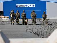 Soldaten stehen vor einer Lagerhalle im Hafen