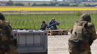 Soldaten verteidigen sich gegen zwei Angreifer, die den Stacheldraht durchschnitten haben