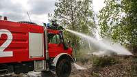 Ein Feuerwehrfahrzeug löscht einen Brand in der Natur. 