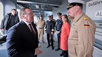 Ein Marinesoldat in sandfarbener Uniform grüßt einen Zivilisten im Straßenanzug militärisch.