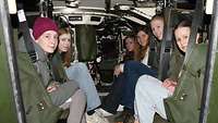 A group of young women sitting in a military vehicle.