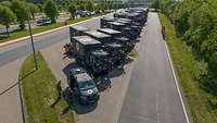 Viele Bundeswehrfahrzeuge nebeneinander auf einem Parkplatz.