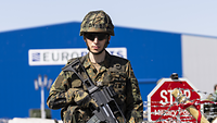Ein Soldat steht mit seinem Gewehr vor einer Absperrung