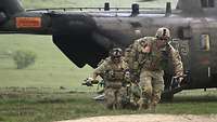Soldaten verlassen rennend das geöffnete Heck eines gerade gelandeten Hubschraubers