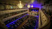 Ein Orchester auf einer Bühne in einem großen Saal