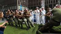 Soldiers in camouflage uniforms playing tug-of-war against each other.