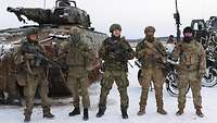 Fünf Soldaten aus unterschiedlichen Nationen stehen mit ihren Sturmgewehren vor einem Schützenpanzer Puma