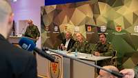 Mehrere Soldaten und ein Mann in Zivil sitzen am Pult im Rahmen einer Pressekonferenz der Bundeswehr