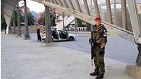 Ein Feldjäger steht mit einem Gewehr vor einer Brücke, im Hintergund Polizisten aus Kosovo