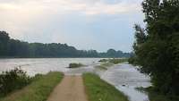 Ein Feldweg wird vom Hochwasser überspült