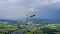 Ein Eurofighter fliegt über die Landschaft von Lettland