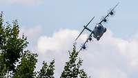 Ein Transportflugzeug der Bundeswehr fliegt bei wolkig-sonnigem Wetter am Himmel.