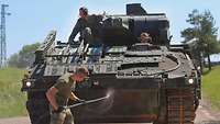 Ein slowakischer Soldat desinfiziert einen Schützenpanzer Puma mithilfe eines Hochdruckreinigers
