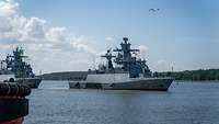 A gray German Navy warship leaves the harbor.