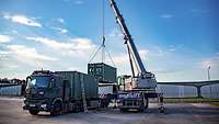 Ein Kran hievt einen Container auf einen Lkw