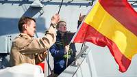 Zwei Soldaten hissen eine rot-gelb gestreifte Flagge.