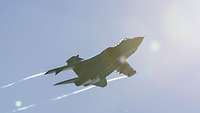 A fighter jet flies in the sunny sky.