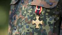 Ein Soldat trägt das Ehrenkreuz der Bundeswehr für Tapferkeit an dem Flecktarn