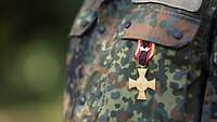 Nahaufnahme eines Ehrenkreuzes an der Tarnfleck-Uniform.