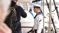 Ein Marinesoldat spricht mit einem Zivilisten auf einem Segelschiff