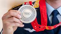 Eine Silbermedaille mit der Gravur "XXIV Olympic Winter Games Beijing 2022" in der Hand eines Soldaten