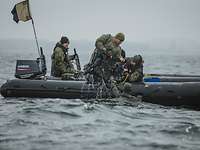 Zwei Soldaten auf einem Schlauchboot ziehen die Tauchausrüstung aus dem Wasser, der Taucher hängt am Boot
