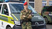 Eine Soldatin in Uniform vor einem Fahrzeug der Feldjäger