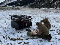 Zwei Soldaten knien an einer Dummy-Puppe, daneben steht ein kastenförmiger Roboter mit Trageaufbau.
