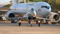 A fighter jet in front of a large aircraft.