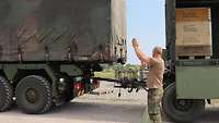 Ein Soldat gibt Handzeichen, damit der Kraftfahrer eines Lkw einen Anhänger ankuppeln kann.