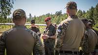 Mittig steht ein Soldat umringt von weiteren Soldaten verschiedener Nationen