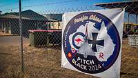 A fence with a poster showing a fighter jet in front of a map of Australia.