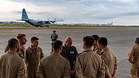 The air chief of the German Air Force stands together with the soldiers on a runway.