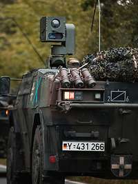 Zwei Militärfahrzeuge fahren auf einer Straße hintereinander.