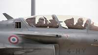 Two pilots sit in a closed cockpit of a fighter jet.