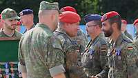 Mehrere Soldaten stehen in Formation. davor schüttelt eine weiterer Soldat die Hand eines Soldaten..