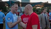 Two men greet each other in running shirts.